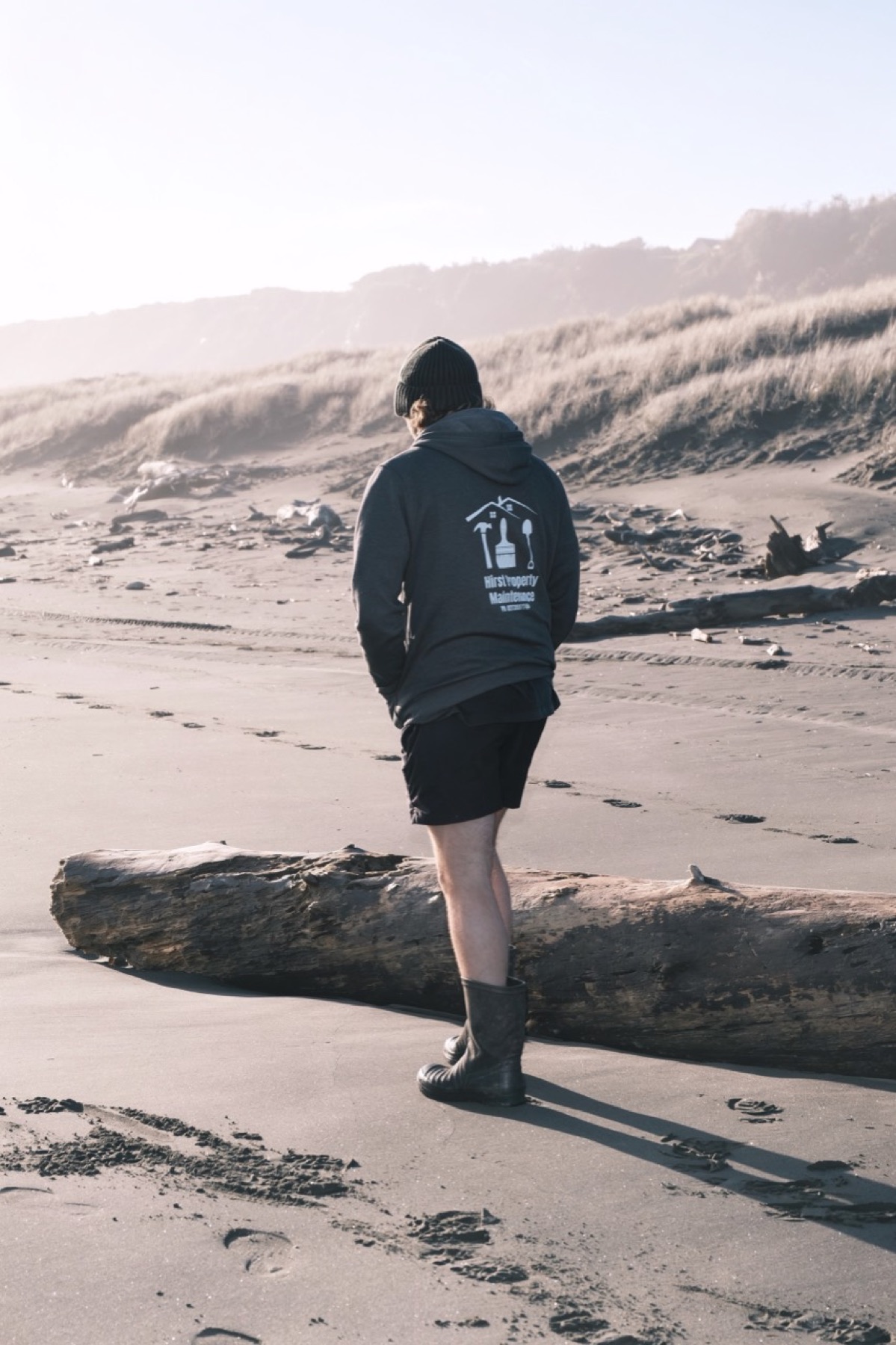 Property maintenance worker walking past driftwood on a wide beach