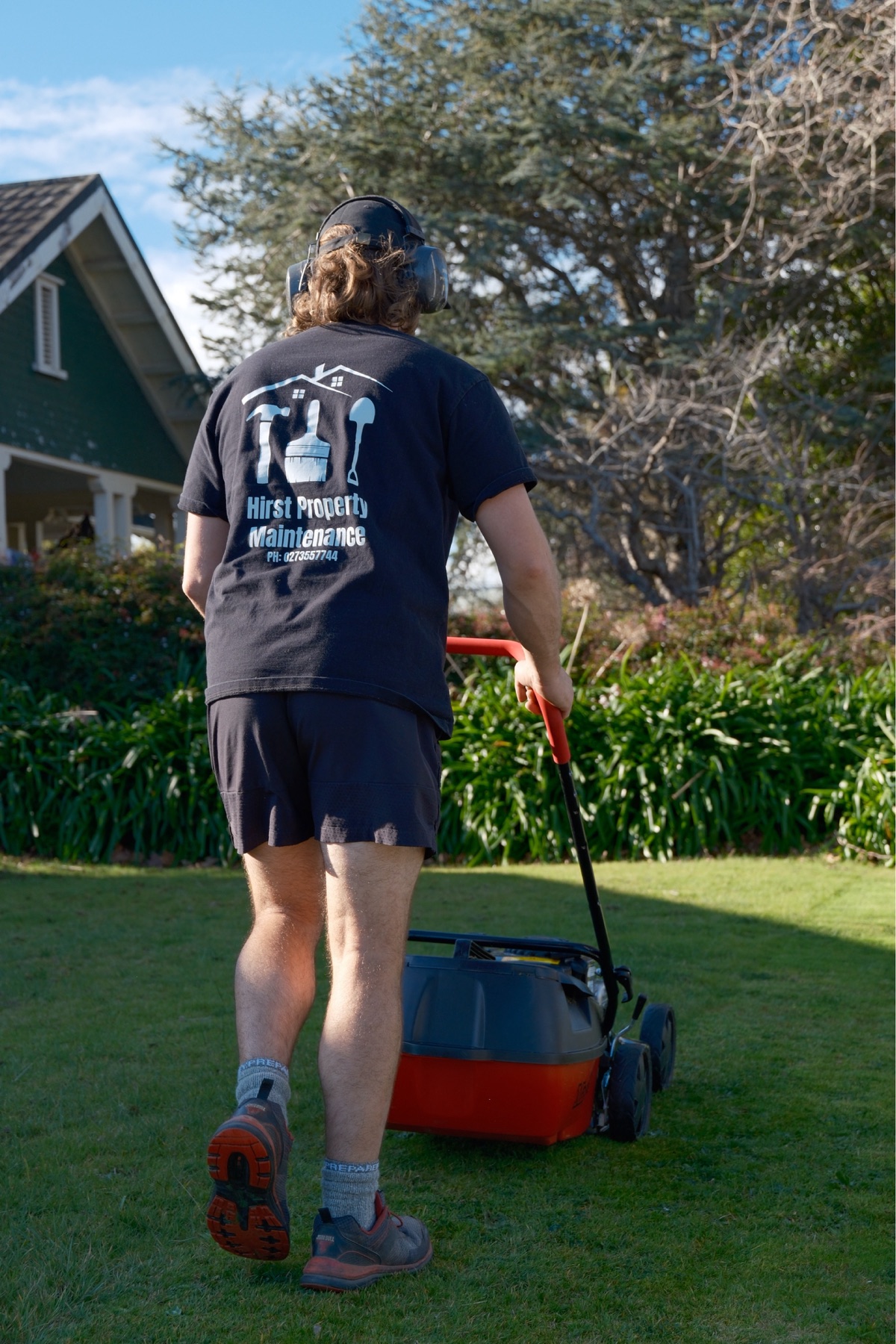 Maintenance worker mowing a residential lawn