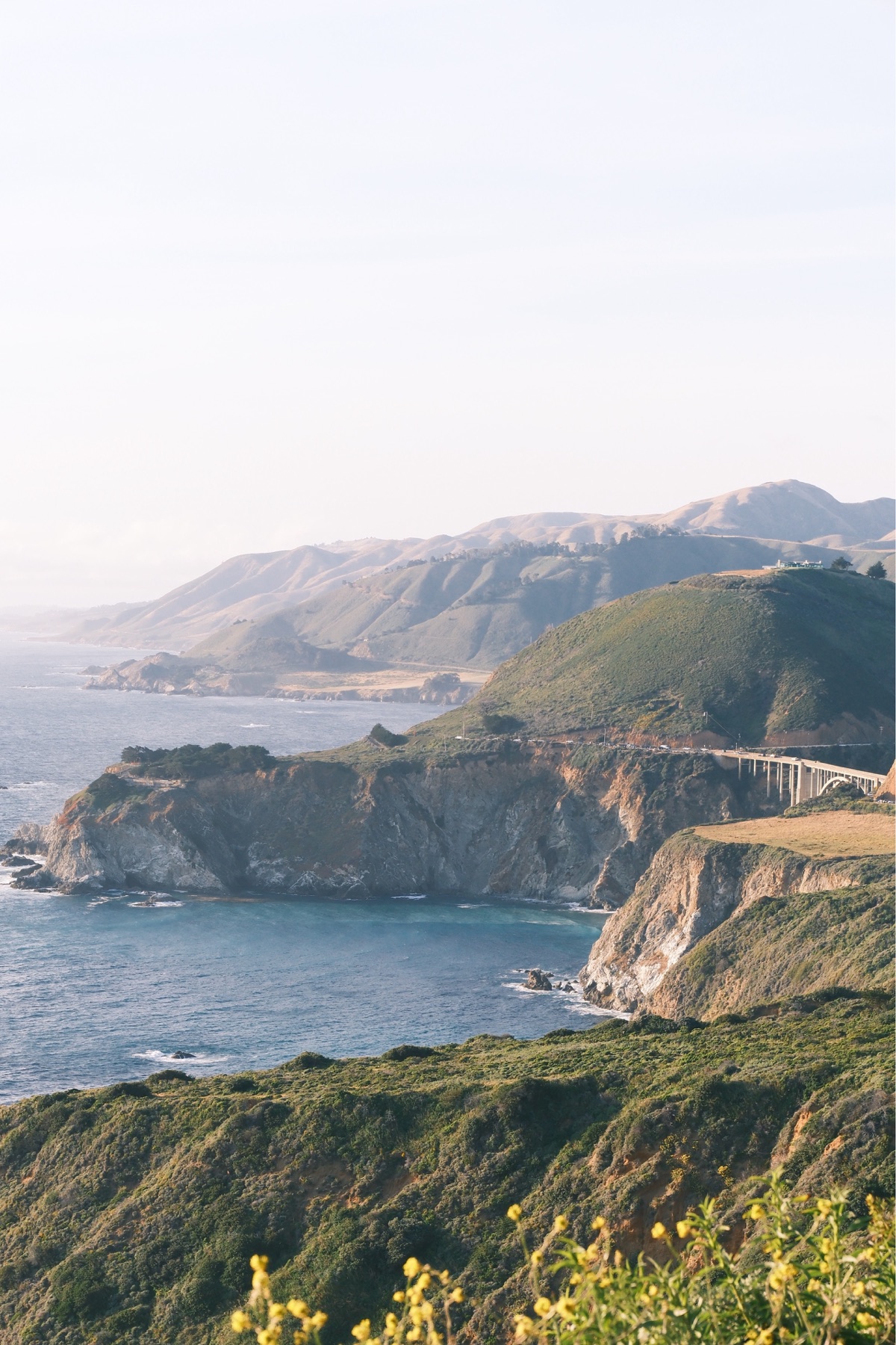 Sunlit cliffs and a winding bridge along the California coast