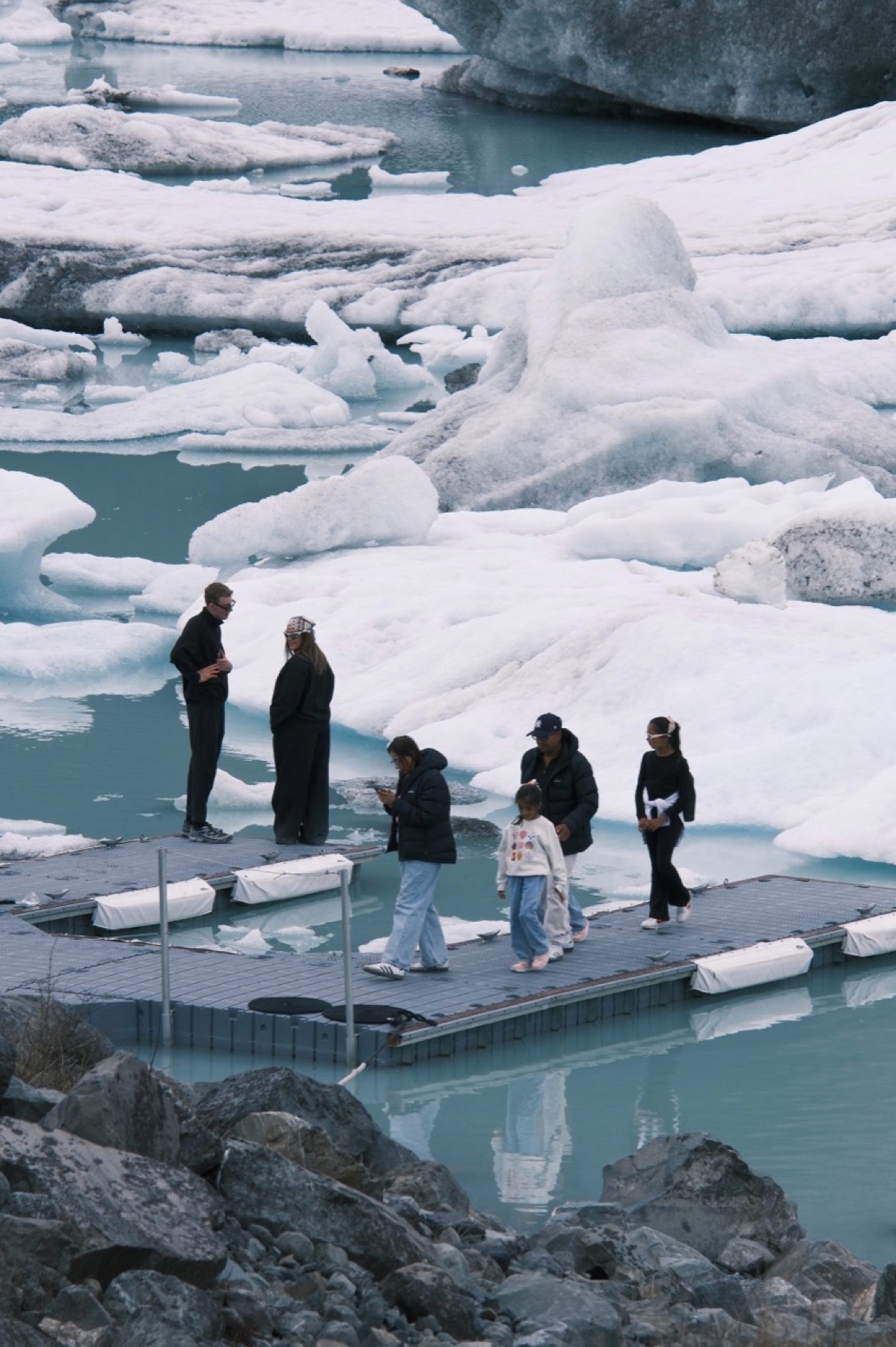 Travellers crossing a floating dock through an ice lagoon