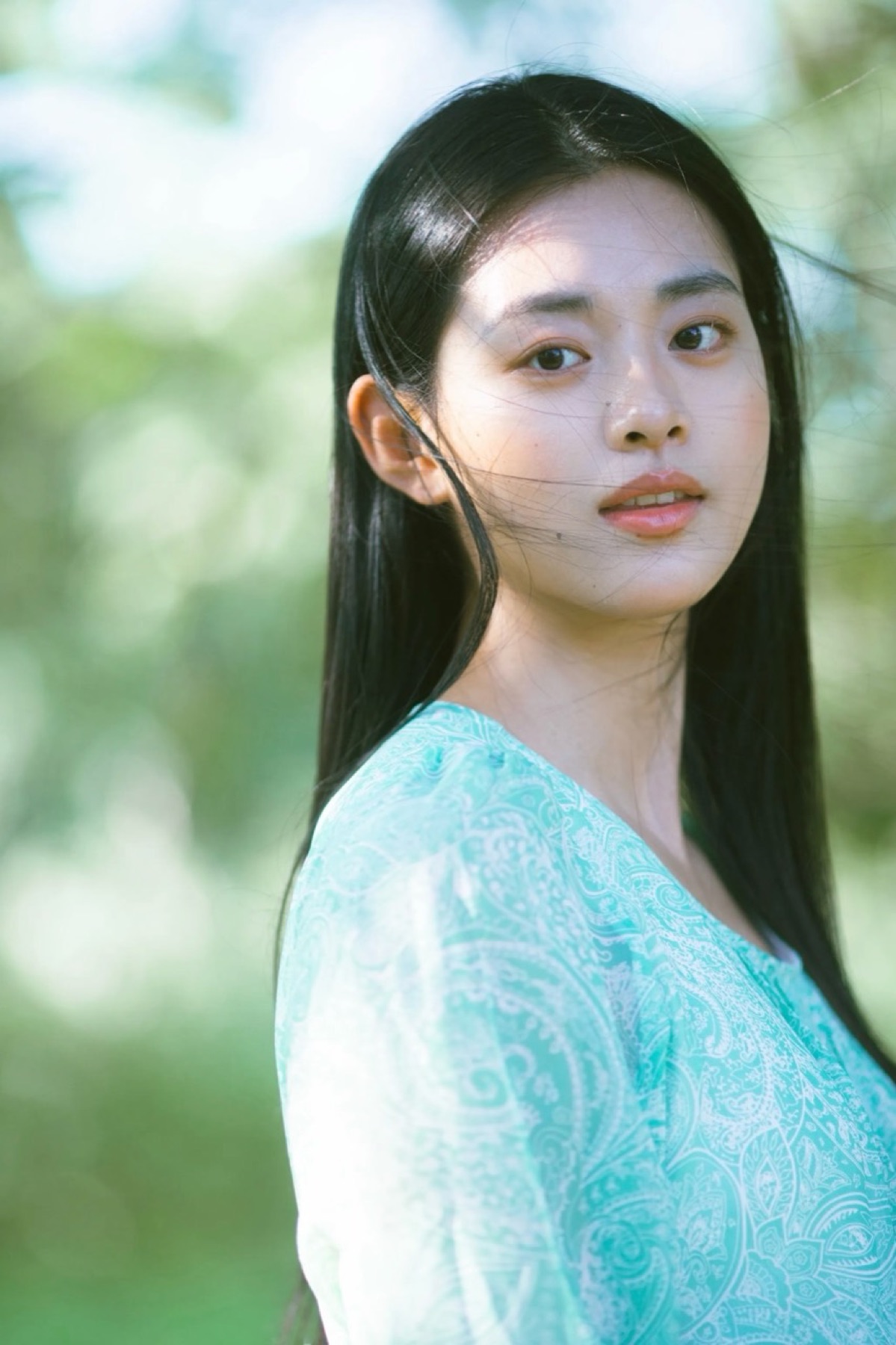 Woman in mint green looking over her shoulder in a garden